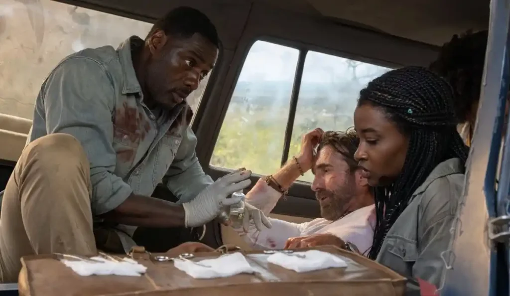 Idris Elba dentro de carro em estrada de terra com expressão de tensão em A Fera.
