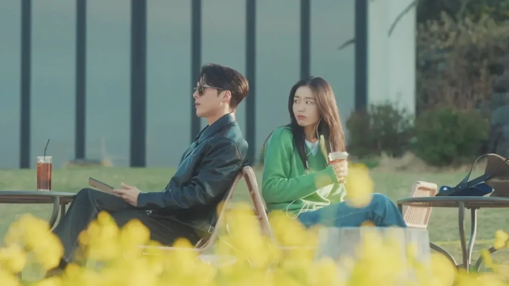 Go Da-rim e Gong Ji-hyeok sentados de costas um para o outro, em cena ao ar livre do dorama Beijo Explosivo