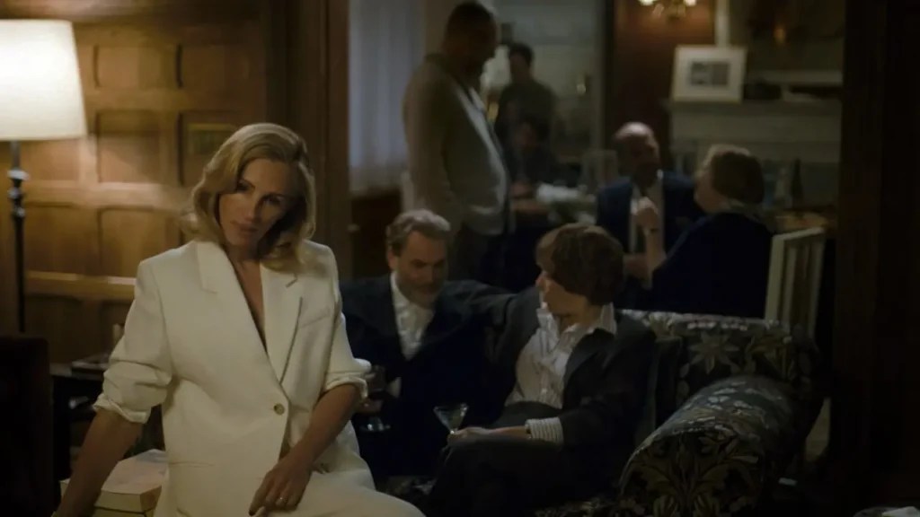 Julia Roberts vestida de branco sentada em uma sala repleta de professores em cena de Depois da Caçada.