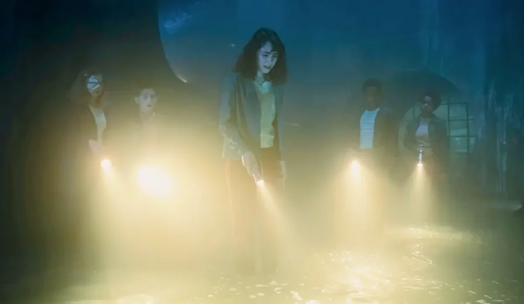 Túneis subterrâneos iluminados por lanternas em cena do episódio 5 de IT: Bem-Vindos a Derry