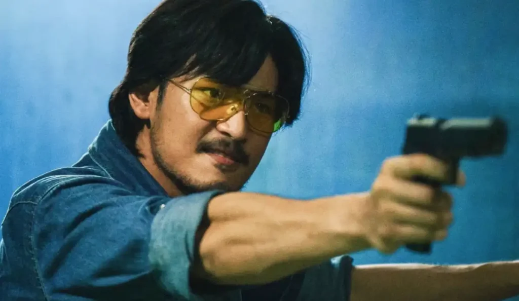 Imagem de Tee Yai encarando um rival em ambiente urbano noturno.