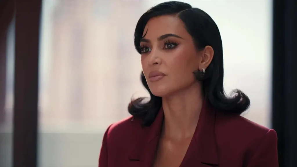 Personagem de Kim Kardashian aparece em close, usando blazer vermelho e expressão concentrada em Tudo É Justo