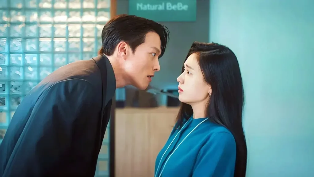 Ji-hyeok inclinado olhando fixamente para Da-rim em ambiente corporativo no dorama Beijo Explosivo.