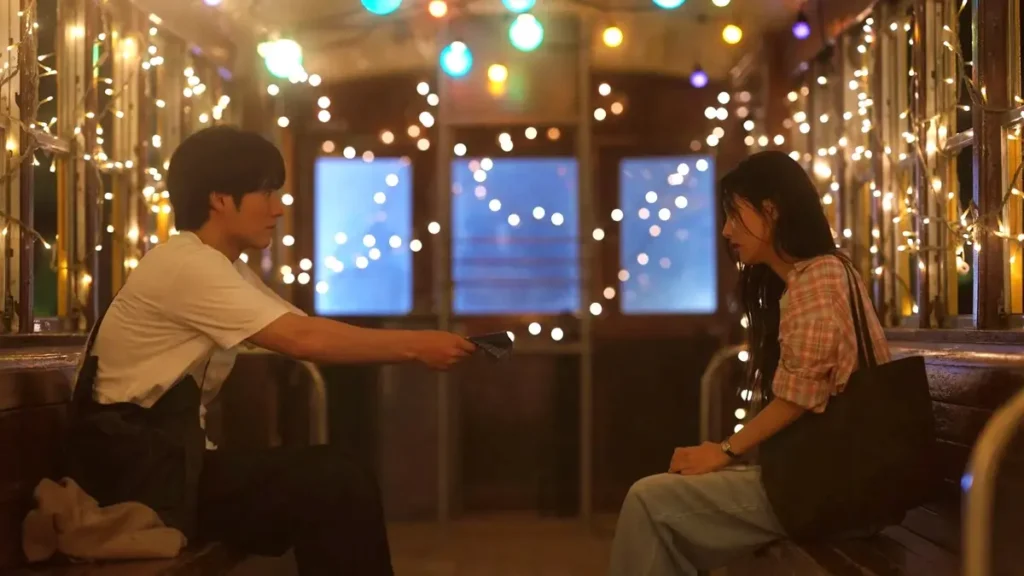 Rin e Taiga sentados frente a frente em um vagão iluminado por luzes, em cena intimista do dorama Bolinhos de Arroz, da Netflix