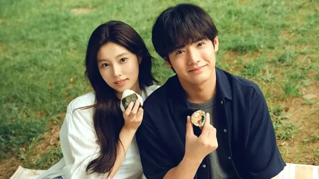 Casal protagonista segura bolinhos de arroz em cena ao ar livre do dorama Bolinhos de Arroz, disponível na Netflix