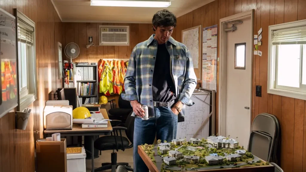 Personagem de Jacob Elordi em Euphoria analisando maquete imobiliária em escritório