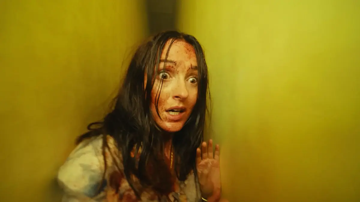Mary aparece assustada e ferida em um corredor amarelo das Backrooms no filme Backrooms: Um Não-Lugar.