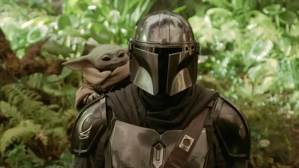 Grogu aparece no ombro de Din Djarin em cena de O Mandaloriano e Grogu, nova aventura de Star Wars nos cinemas.