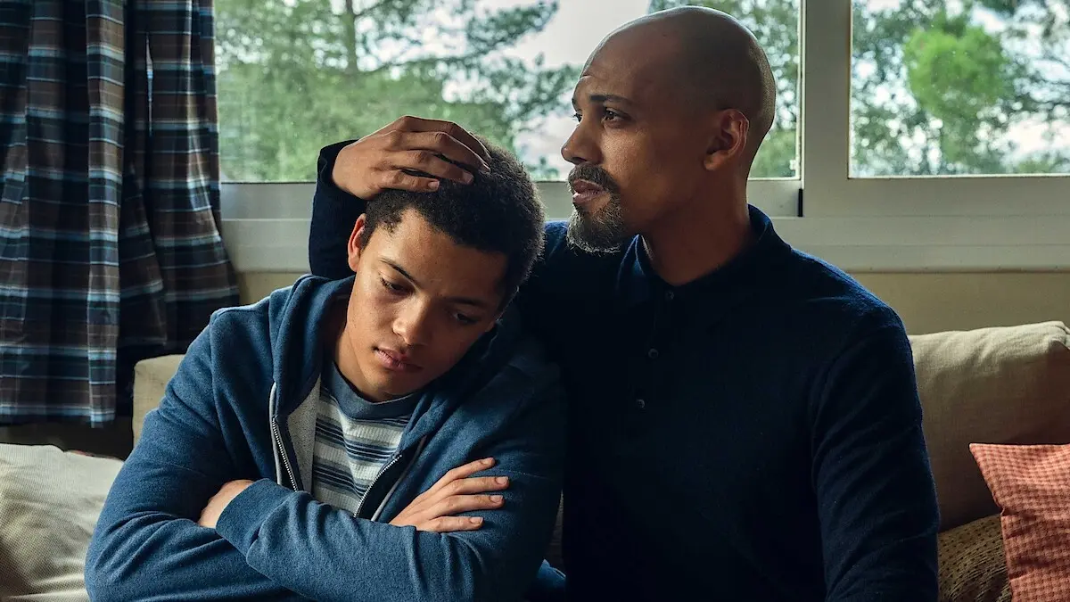 Cena da minissérie A Testemunha mostra pai e filho sentados juntos em momento dramático da produção da Netflix
