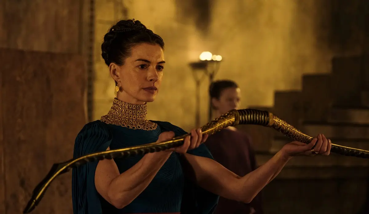 Anne Hathaway aparece como Penélope segurando um arco dourado em A Odisseia